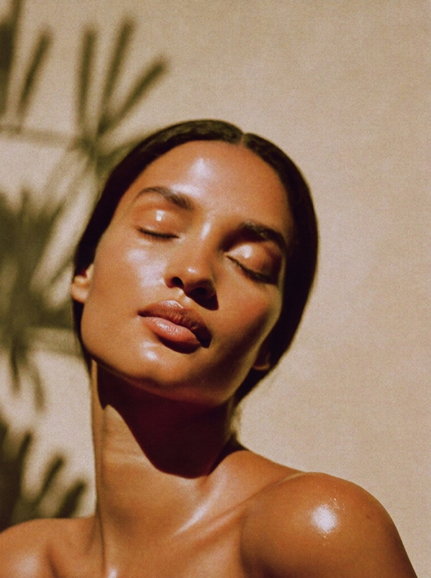 Serene woman with glowing skin, face tilted toward warm golden sunlight
