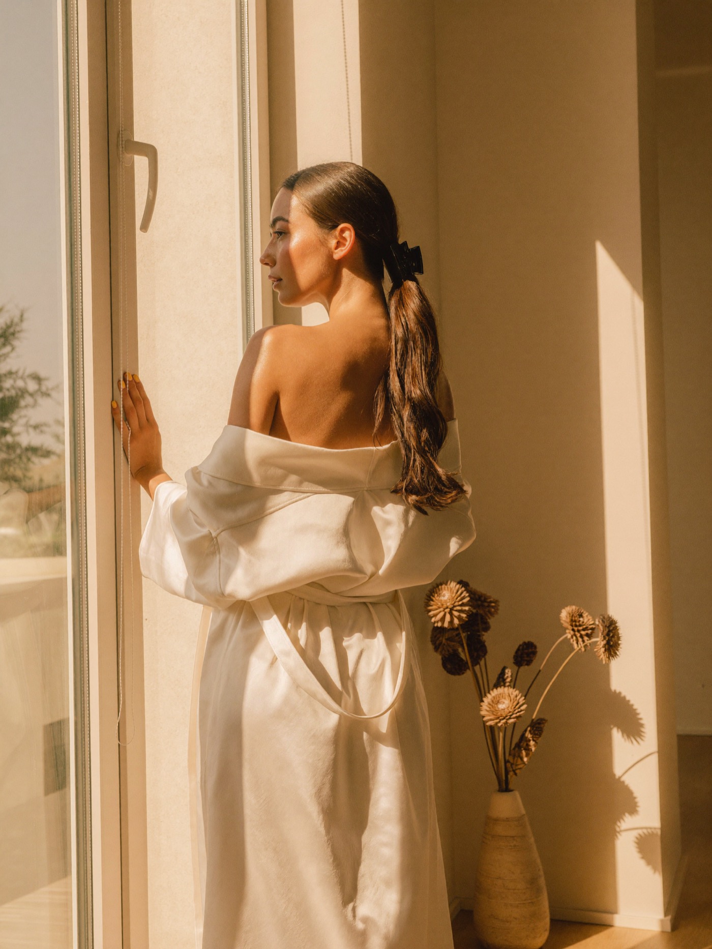 Woman in a robe standing in warm window light