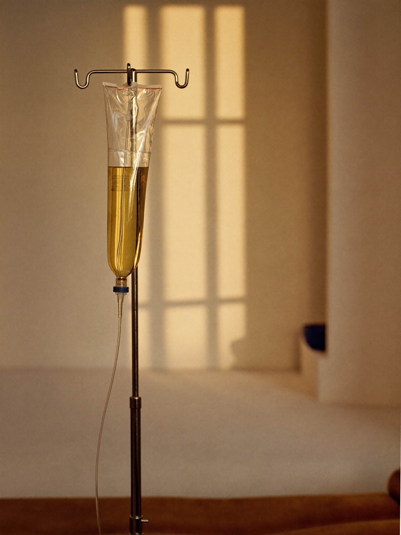 IV therapy drip bag with golden liquid in warm sunlight