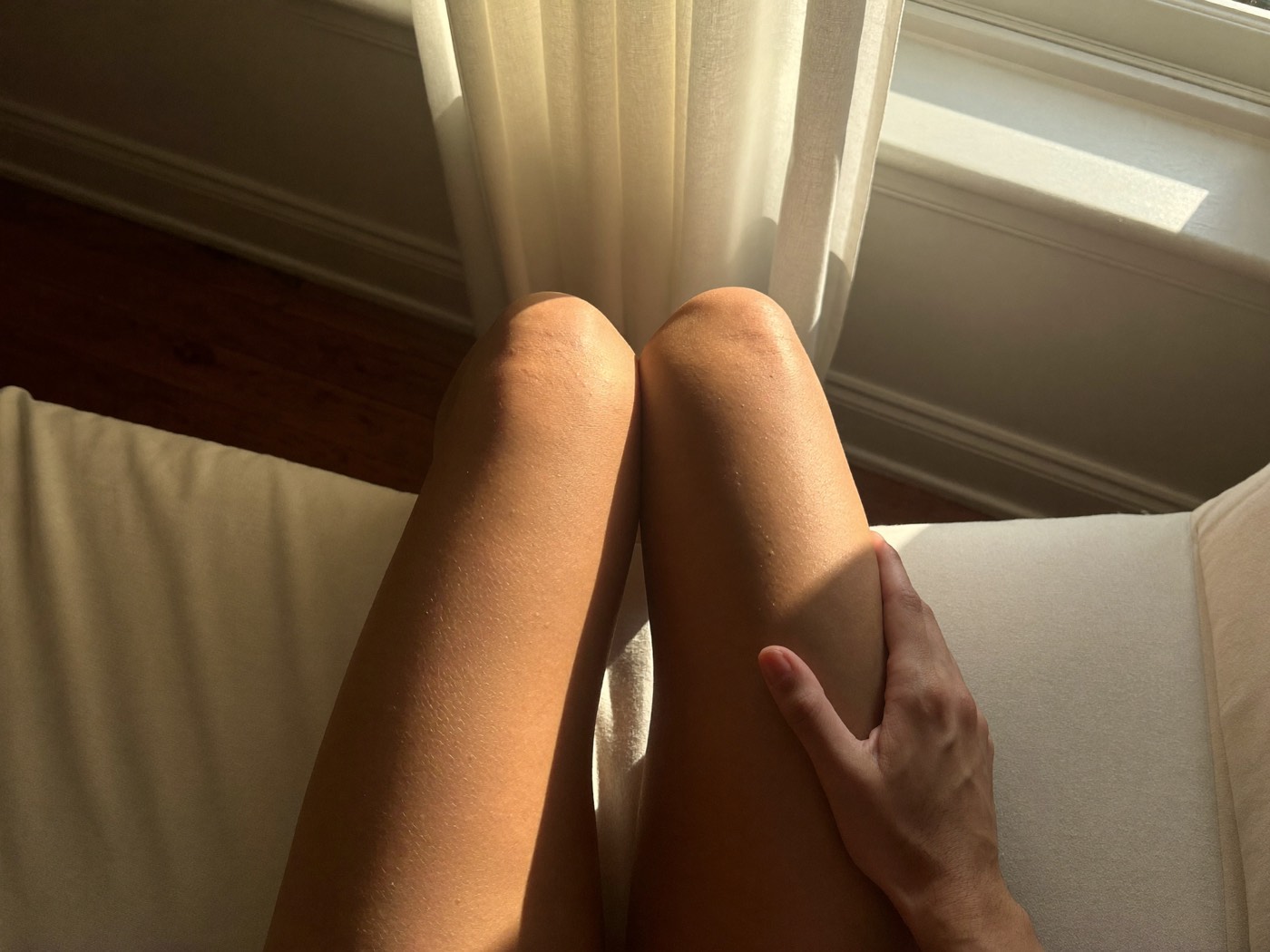Smooth bare legs resting by a sunlit window